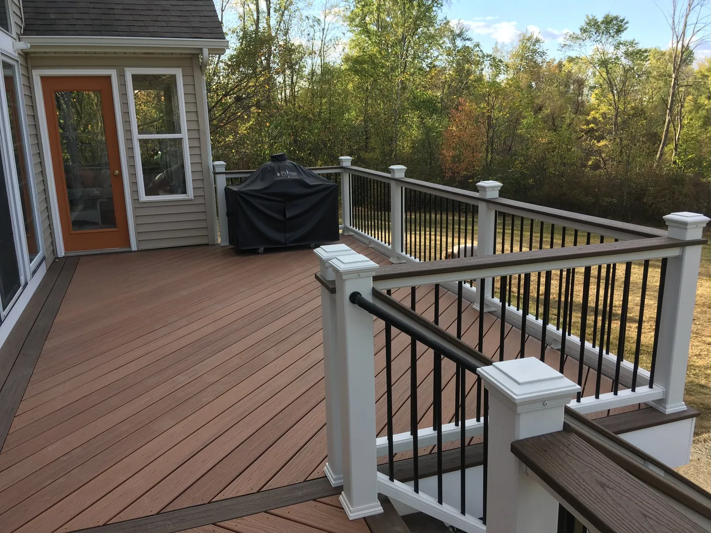 Composite deck with white posts and black balusters overlooking trees.