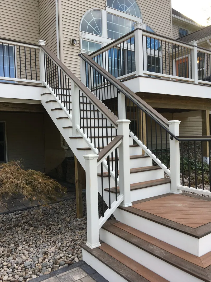 Deck stairs with a landing, white posts and black balusters.
