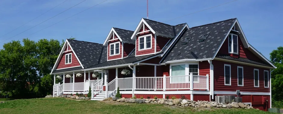Red-sided home with white trim, three dormers and a dark shingle roof.
