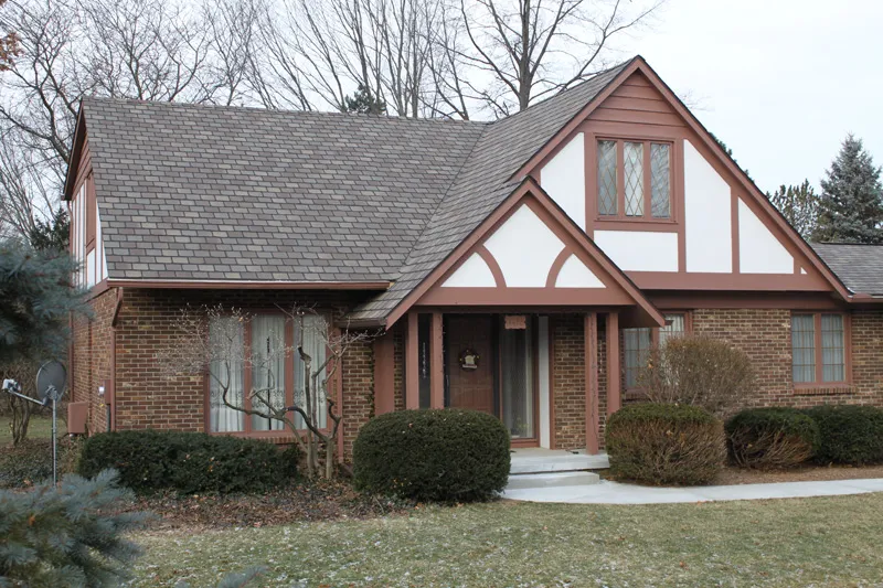 Tudor-style brick home with a slate-look shingle roof.