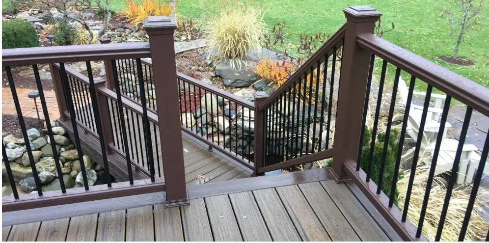 Composite deck with brown rails and black balusters stepping down to a garden.
