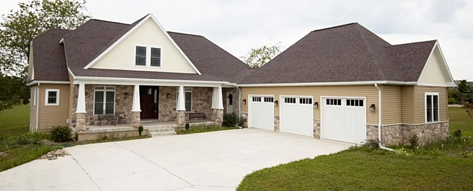 Ranch home with tan siding, stone accents, a covered porch and a three-car garage.