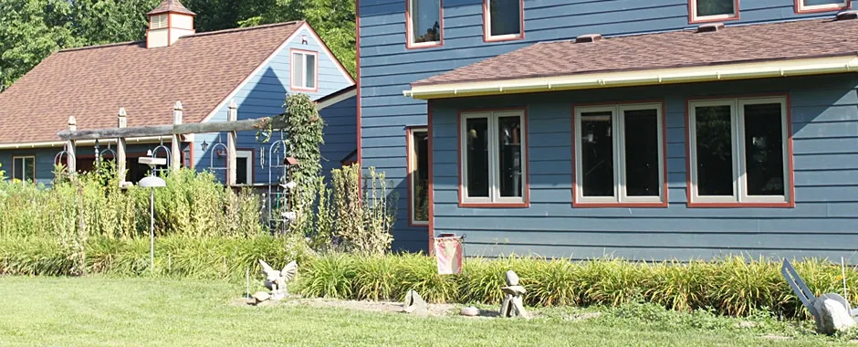 Blue-sided home with rows of red-trimmed casement windows.