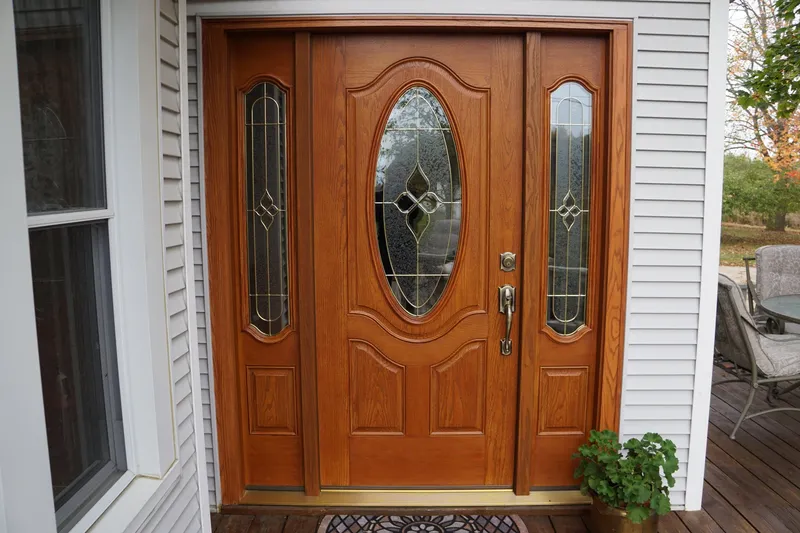 Wood-grain entry door with an oval glass insert and matching sidelights.