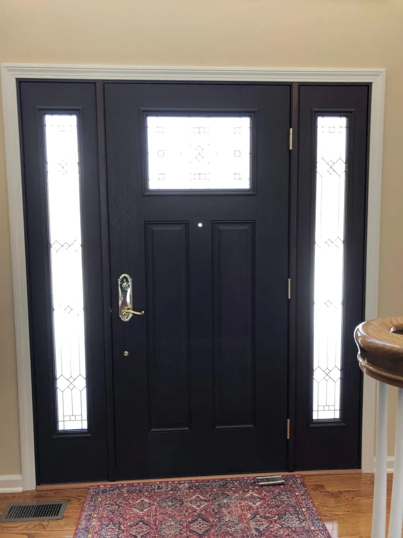 Black entry door with patterned glass sidelights, seen from inside.
